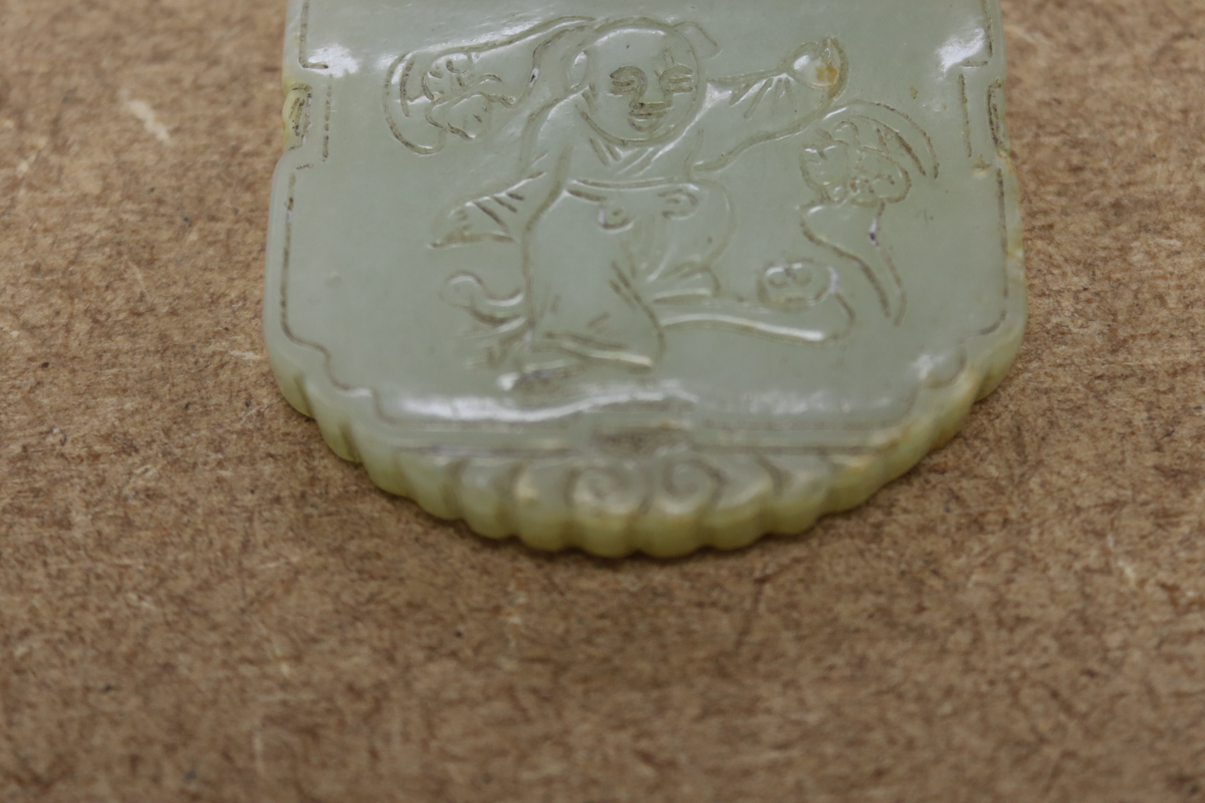 A Chinese pale celadon jade plaque, boy and bats, 5cm wide
